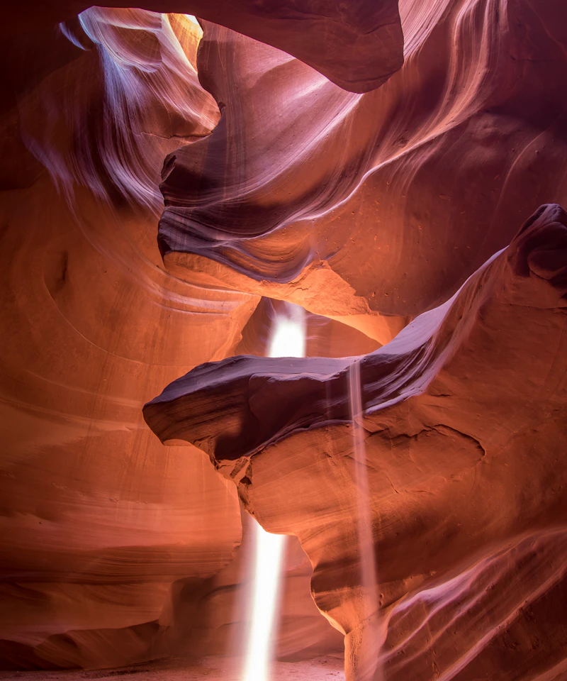 A shaft of sunlight falls through the sculpted red walls of Antelope Canyon