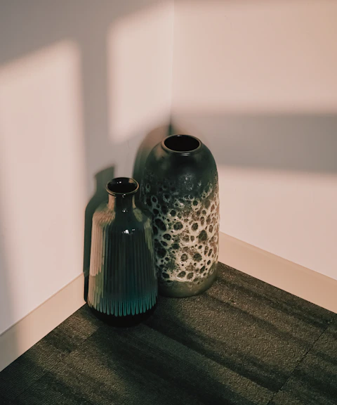 Two green ceramic vases with soft afternoon shadows