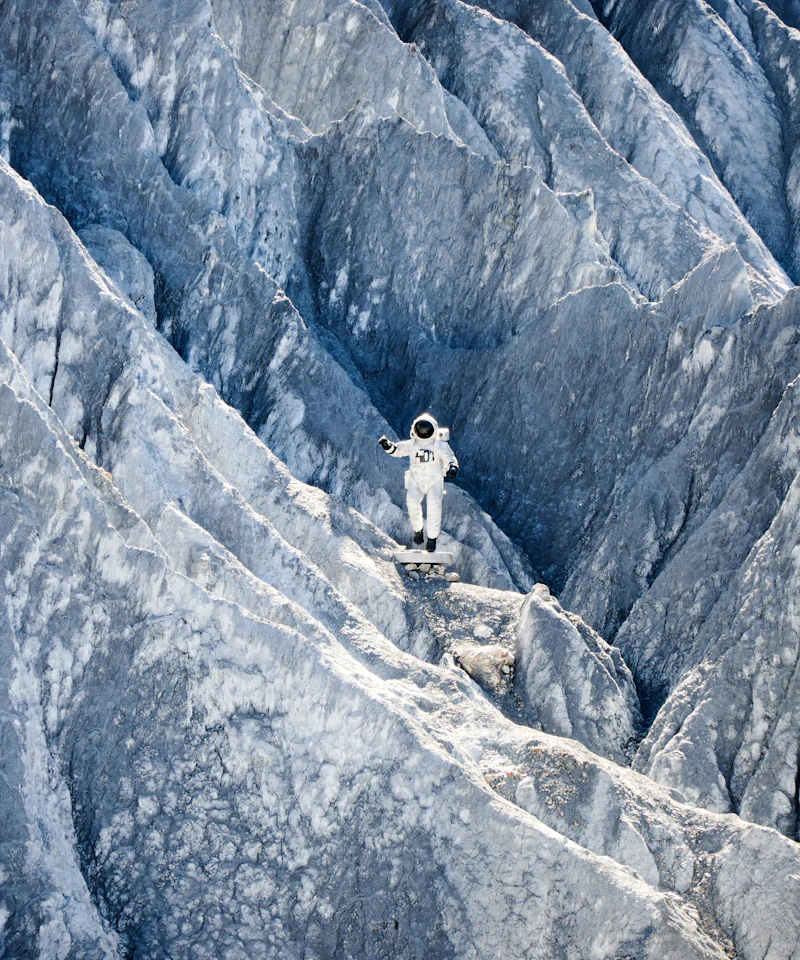 A small white-suited astronaut figure amid jagged blue rocky terrain
