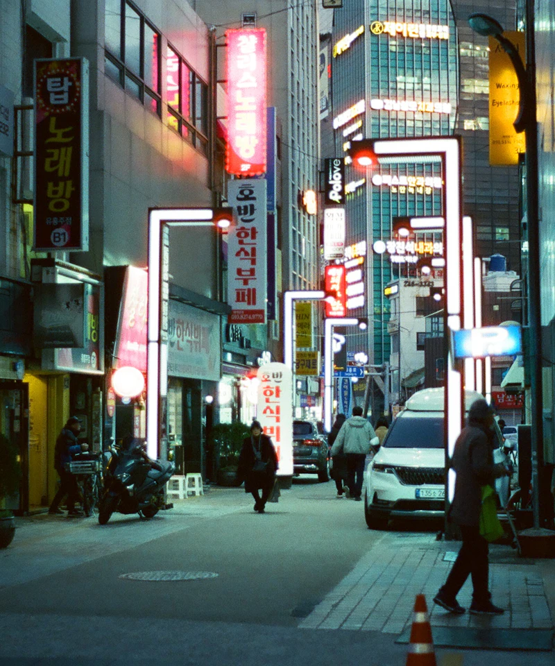 Pedestrians on a city street illuminated by neon signs at night